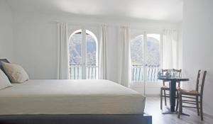 a white bedroom with a bed and two windows at Locanda Gandriese in Gandria