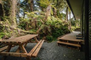 dos mesas de picnic de madera sentadas fuera de una cabaña en Forest View Franz Josef, en Franz Josef