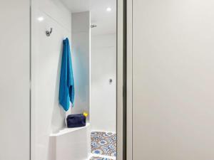 une porte pivotante dans une chambre blanche avec un parapluie bleu dans l'établissement HOTELF1 Le Havre Est - Gonfreville, à Gonfreville-l'Orcher