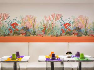 two tables in a restaurant with a flower mural on the wall at ibis Styles Paris Boulogne Marcel Sembat in Boulogne-Billancourt