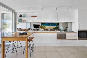 a kitchen with white cabinets and a wooden table at Noosa Views Apartment 4 in Noosa Heads