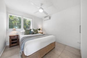 a white bedroom with a bed and a window at Noosa Views Apartment 4 in Noosa Heads