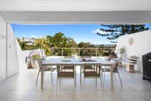 a white dining room with a white table and chairs at Noosa Views Apartment 4 in Noosa Heads