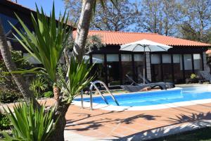 a pool with an umbrella next to a house at Alagoas4Family - Country House in Arouca