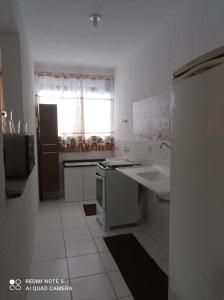 a white kitchen with a sink and a stove at Apto se sentindo em casa in Campos dos Goytacazes