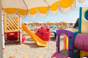 un parque infantil en una playa con sombrilla en Appartamenti CALDERONE, en Rímini