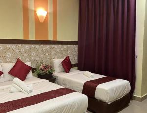 two beds in a hotel room with red curtains at Sun Inns Hotel Meru Raya in Chemor