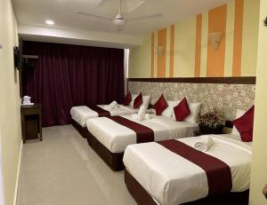 a hotel room with three beds with red pillows at Sun Inns Hotel Meru Raya in Chemor