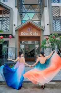 two women in dresses holding hands in front of a store at Eden Home&Cafe in Quy Nhon