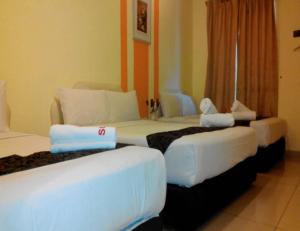 um quarto com três camas num quarto de hotel em Sun Inns Tambun em Kampong Batu Lapan