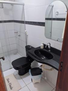 La salle de bains est pourvue de toilettes noires et d'un lavabo. dans l'établissement Apartamento Amplo e familiar em frente à Igreja do Céu, à Viçosa do Ceará
