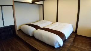 two beds in a room with white pillows at FUTO HOUSE -Ippon no Enpitsu- in Ito