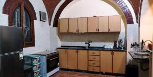 cocina con armarios de madera, fregadero y nevera en The Healing House en Luxor