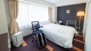 a hotel room with a bed and a chair at Hotel Shin Osaka in Osaka