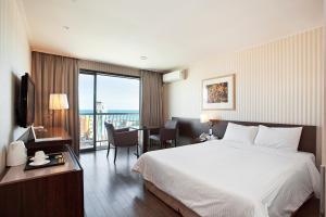 a hotel room with a large bed and a large window at Songjung Hotel in Busan