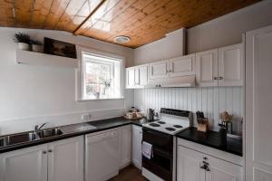 a kitchen with white cabinets and a black stove top oven at Berwick Cottage in Hobart