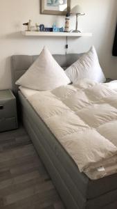 a bed with white sheets and pillows in a room at FeWo "Montymar" incl. Strandkorb in Grömitz