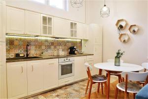 une cuisine avec des placards blancs et une table avec des chaises dans l'établissement Apartament Palatul Stern, à Oradea