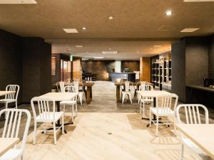 a dining room with tables and white chairs at Hotel Area One Ise Inter in Ise