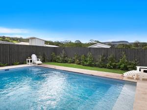 a swimming pool with two chairs and a fence at Elm Cottage in Berry