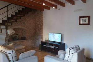 a living room with two white chairs and a television at CASA LLEÓ in Pollença