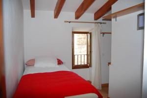 a red bed in a white room with a window at CASA LLEÓ in Pollença