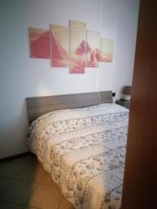 a bed in a bedroom with four pictures on the wall at B&B La casa dei frutti di bosco in Garlasco