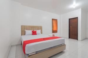 een slaapkamer met een groot bed en een rode deken bij RedDoorz at Vall Guest House Balikpapan in Balikpapan