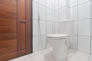 een badkamer met een wit toilet en een douche bij RedDoorz at Vall Guest House Balikpapan in Balikpapan