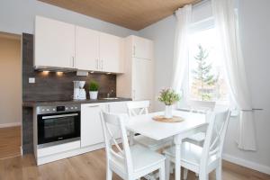 una cocina con armarios blancos y una mesa y sillas blancas. en Seestraße 30 a Im Kornspeicher, en Dahme