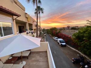 an umbrella on a balcony of a house with a sunset at Loft playa Torviscas,garaje gratis , recién reformado in Adeje