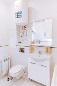 Baño blanco con aseo y lavamanos en Hotel Nika, en Yessentuki