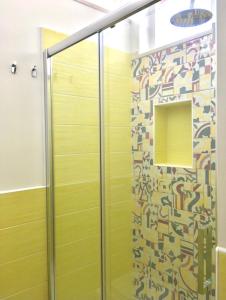 a shower with yellow walls and a mirror at Puntamare House in Peschici