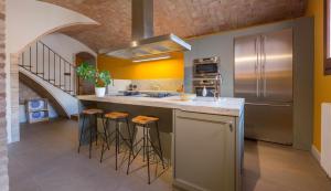 a kitchen with a sink and a counter with stools at Masia Les Apieres in El Pla de Manlleu