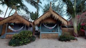 a blue house with straw huts and palm trees at Sea Love Beach Bar & Bungalows in Ban Tai