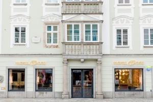 a white building with two store fronts with windows at Motel One Linz-Hauptplatz in Linz