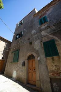 un edificio de piedra con persianas verdes y una puerta en CasaMatta2, en Isola del Giglio