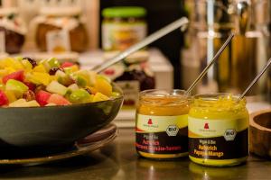 a bowl of fruit next to two jars of honey at Motel One Wien-Hauptbahnhof in Vienna