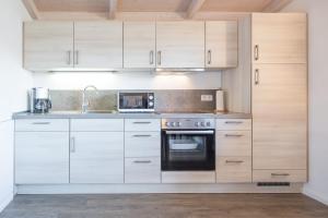 a kitchen with white cabinets and a stove top oven at Ferienhaus Oland in Dagebüll