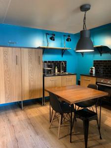 a kitchen with a wooden table and a blue wall at Les Cloutiers in Chalon-sur-Saône