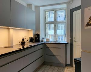 コペンハーゲンにあるApartmentInCopenhagen Apartment 720の白いキャビネットと窓付きのキッチン