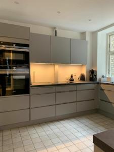 コペンハーゲンにあるApartmentInCopenhagen Apartment 720の白いタイルフロアのキッチン(白いキャビネット付)