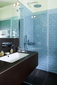a blue tiled bathroom with a sink and a shower at Clipper Boardinghouse - Berlin-Gendarmenmarkt in Berlin +10 photos