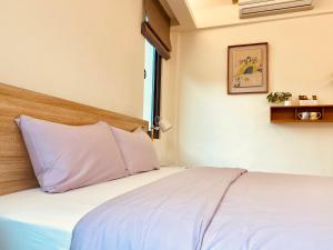 1 dormitorio con cama blanca y ventana en Literature River Bank 文學河岸 禁菸小包棟民宿, en Hualien City