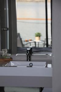 ein Waschbecken mit einem Wasserhahn vor dem Spiegel in der Unterkunft Les Ilots de Gruissan in Gruissan