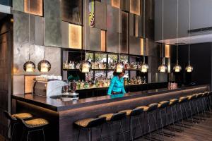 a woman standing behind a bar in a restaurant at Motel One Wien Westbahnhof in Vienna