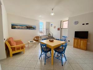 Il Riccio Apartment في بروسيدا: غرفة معيشة مع طاولة وكراسي وتلفزيون