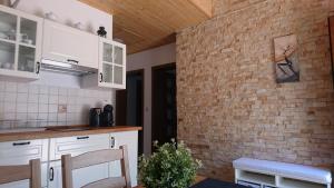 uma cozinha com armários brancos e uma parede de tijolos em CORNER Vendégház em Veszprém