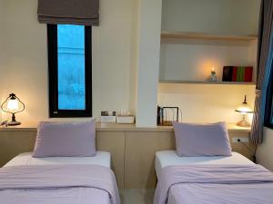 two beds in a room with purple pillows at Literature River Bank 文學河岸 禁菸小包棟民宿 in Hualien City