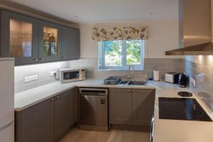 a kitchen with gray cabinets and a sink at Cliff House Holiday Cottages in Ebberston